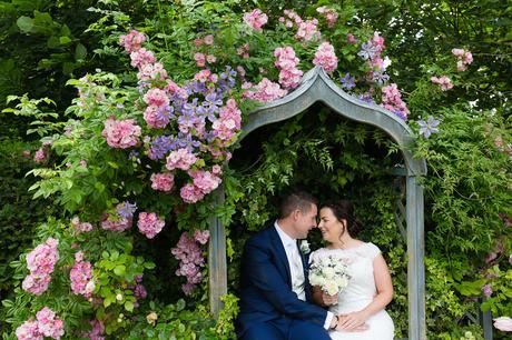 Bell Hall Wedding Photography brid eand groom cuddling in garden seat surrounded by hydrangeas