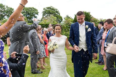Bride and groom walk through confetti at Bell Hall