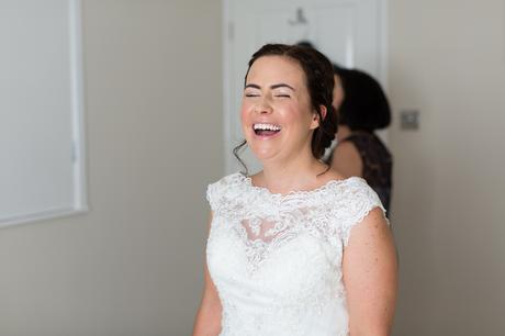 Bride laughing getting into dress. 