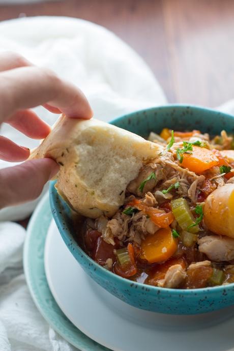 Dunking bread in a bowl of Instant Pot Tuscan Chicken Stew