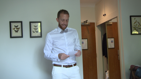 the groom smiles as he reads the wedding card sent by his bride to be waiting at Styal Lodge