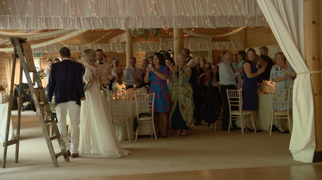 the bride and groom dance through the tables and guests during their entrance for the wedding reception at Styal Lodge in Cheshire caught on the wedding video