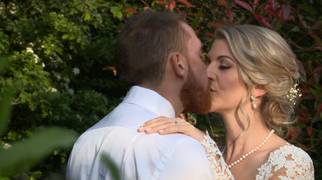 the bride and groom kiss whilst posing for their wedding photographer and videographer at Styal Lodge in Cheshire