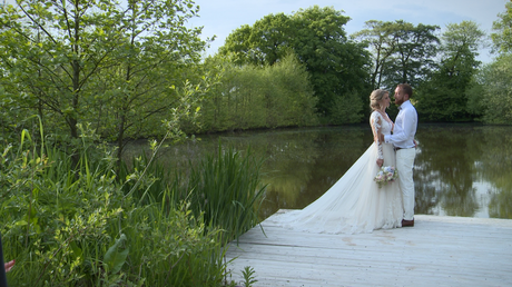 a wider shot of the bride and groom having a chat by the lake Styal Lodge in Cheshire