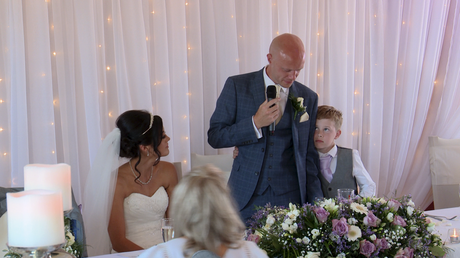 the grooms young son leans in to his dad to give him a hug as he gets emotional during his speech for the wedding video at The Blue Mallard