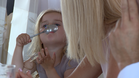 the flower girl makes her nan laugh as she tries to stick a spoon to her nose during the wedding reception