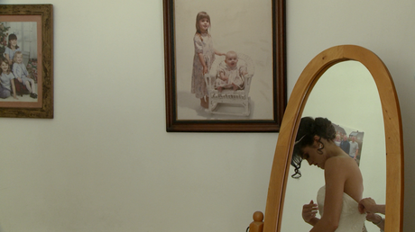 in the mirror you can see the bride getting in to her wedding dress and on the wall are some old vintage photographs of her as a young girl in her parents home in lancashire