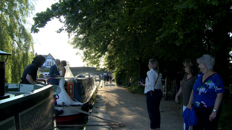 a couple of ladies out walking their dog watch on as the bride and groom enjoy a few couple portraits on a canal boat near burscough wharf after their wedding breakfast