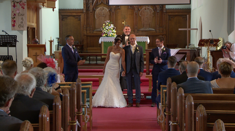 the bride and groom face their wedding guests and wedding videographer as they cheer and clap them being announced as the new Mr and Mrs Disley at St Johns in Burscough lancashire