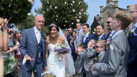 the bride laughs and ducks down as guests shower them in natural flower confetti outside their church in burscough