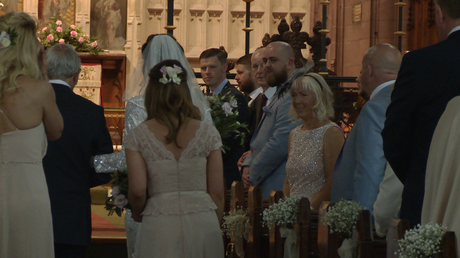 the videographer at the back of St Peters Church in Woolton films the groom turning to see his bride walk towards him