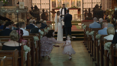 the videographer films a flower girl running down the aisle as her mum tried to catch her during  a wedding ceremony at St Peters in Woolton