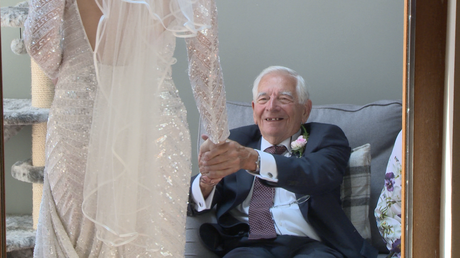 grandad holds his grand daughters hand tightly with pride as he sees her in her wedding dress for the first time