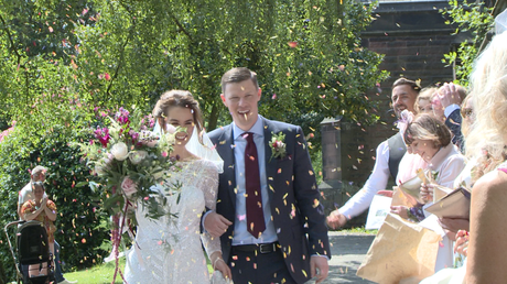 confetti is thrown at the bride and groom as they make their way through the lychgate at st peters in woolton