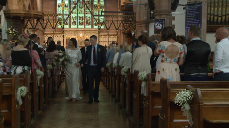 the bride and groom walk back down the aisle as husband and wife at St Peters in Woolton village