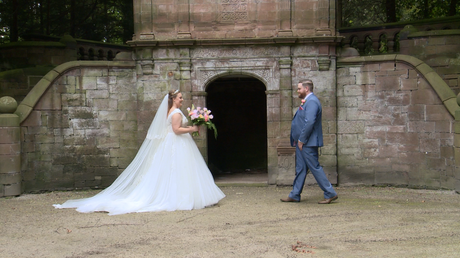 the bride and groom walk towards each other in front of a stone archway at thornton manor