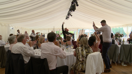 the singing waiter downs a pint much to the amusement of the wedding guests egging him on