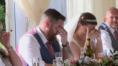 he groom and bride hide their faces in embarrassment during the best man speech
