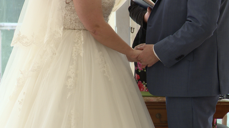 a close up of the bride and groom holding hands during the ceremony
