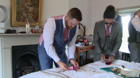 the groom and his usher work out how to fold their pocket squares