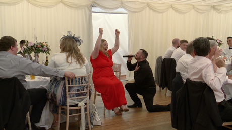 silver service singers on one knee singing to a wedding guests who is so excited to be serenaded she has her hands in the air!