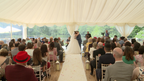 a wide shot of the ceremony as the bride and groom kiss