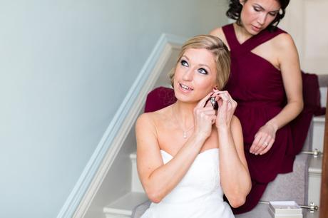 York Wedding Photography at Hornington Manor Farm bride puts in her earrings whilst sitting on the stairs