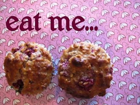 Two raspberry oatmeal muffins pictured from above with the text 'eat me' above them.