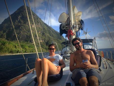 two people on a sailboat with a tropical island