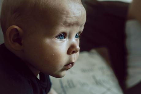 a close up of a little boys face as he watched baby tv with his parents showing off his goreous blue eyes in this beautiful natural family photograph