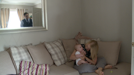 dad pops his head round the door to see if baby has woken from his nap a Mum sit on the sofa