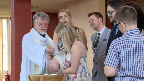 a baby boy gets baptised in front of parents and godparents at st pauls of the cross in Burtonwood