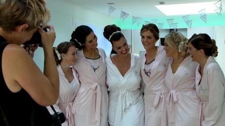 the bride cuddles up with her bridesmaids in their matching wedding robes as they pose for their wedding photographer Jane Hockey