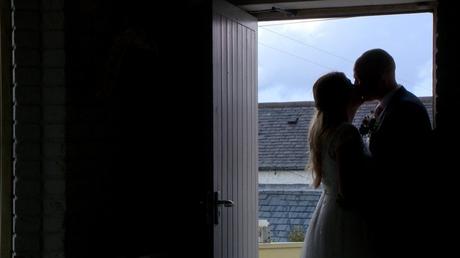a bride and groom enjoy a kiss for the video stood in the doorway of Abel's Harp