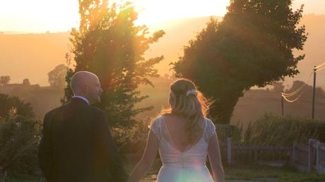 a bride and groom walk and smile with a golden hour liht surrounding them during their wedding evening outside Abel's Harp