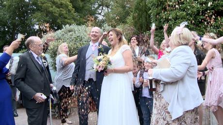 guests laugh and shout out as they shower the bride and groom in dried rose wedding confetti  for the wedding video at Abels Harp