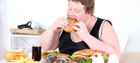 An obese man eating a burger.