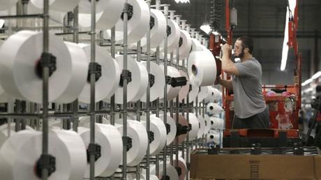 A machine worker unloads spools of thread at a US factory