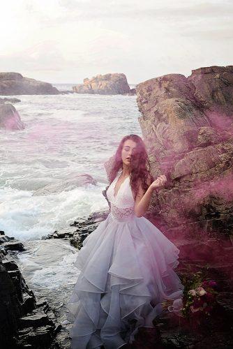 beach styled shoot bride in lace dress among the rocks shrouded in pink smoke alexi