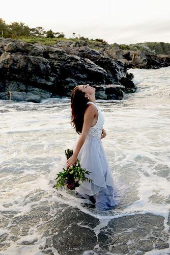 beach styled shoot bride in a white dress is standing in the sea alexi