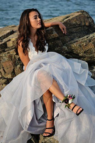 beach styled shoot bride on rocks flower decorating her black shoes alexi