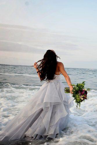 beach styled shoot bride in a white dress with bouquet is standing in the sea alexi