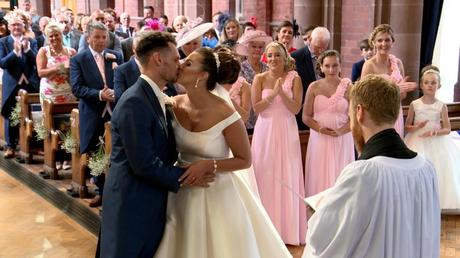 you may kiss the bride as the wedding guests smile and clap behind them at St Saviours church near Birkenhead