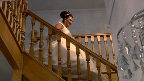 a bride glides down the stairs at her parents home in Prenton wearing an off the shoulder white ellis bridal dress and classic high bun and veil