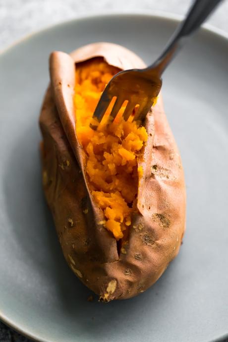 how to bake sweet potatoes- a fork fluffing tender baked sweet potato