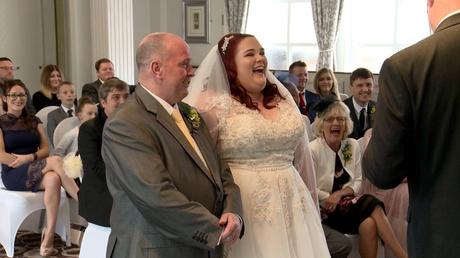 the registrar gets the bride and groom and their wedding guests laughing out loud on the wedding video during a wedding ceremony at Alma Lodge in Stockport