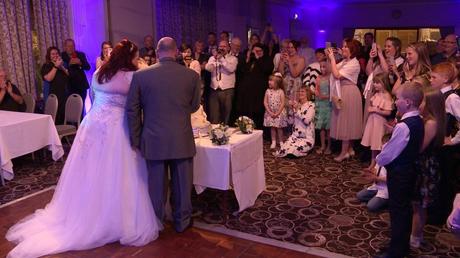 the bride and groom cut their white rose wedding cake for their wedding guests and wedding videographer at Alma Lodge Hotel in Stockport