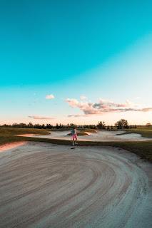 golfer raking bunker