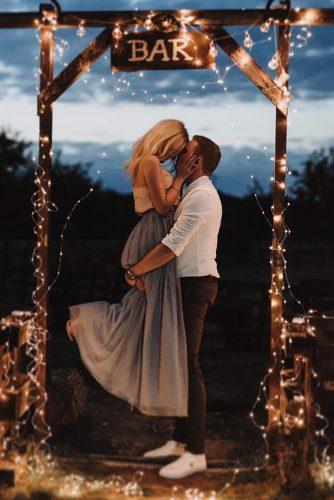 wedding trends 2019 bridal light bulbs arrangement woodland bar sign above the groom and bride kissing above heise_photographie