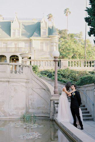 besame wedding styled shoot bride in a dress with a train and the groom in the courtyard of the castle in the italian style near water carrie king photographer
